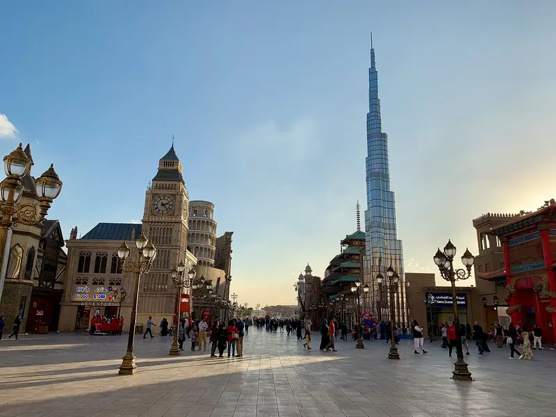 A plaza at Global Village in Dubai with the Burj Khalifa replica rising behind the pavilions