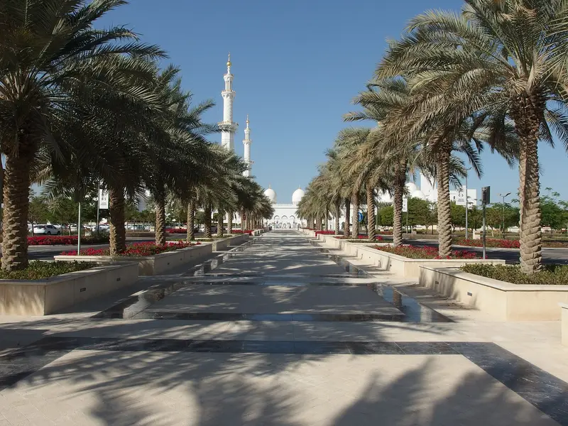 The approach to Sheikh Zayed Grand Mosque in Abu Dhabi, with its white minarets rising beyond the palm-lined walkway